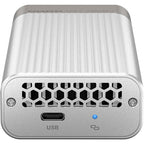 A silver external USB-C enclosure with a ribbed aluminum body, a honeycomb-patterned vent on the front, a USB-C port, and a blue LED indicator light.