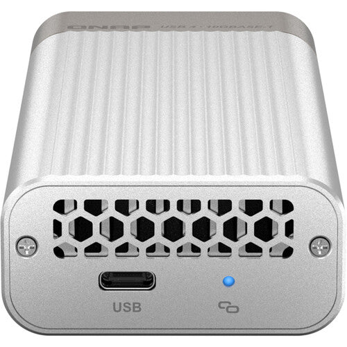 A silver external USB-C enclosure with a ribbed aluminum body, a honeycomb-patterned vent on the front, a USB-C port, and a blue LED indicator light.