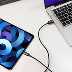 Tablet and laptop connected by a cable on a white surface