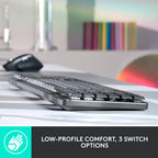 A close-up of a slim black and gray keyboard on a desk, with a mouse blurred in the background. A dark banner at the bottom reads 'LOW-PROFILE COMFORT, 3 SWITCH OPTIONS' with a teal hand icon.