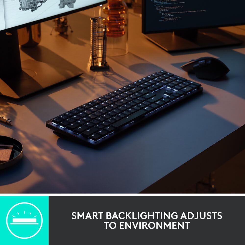 Keyboard on a desk with computer monitors and a mouse, featuring adjustable backlighting.
