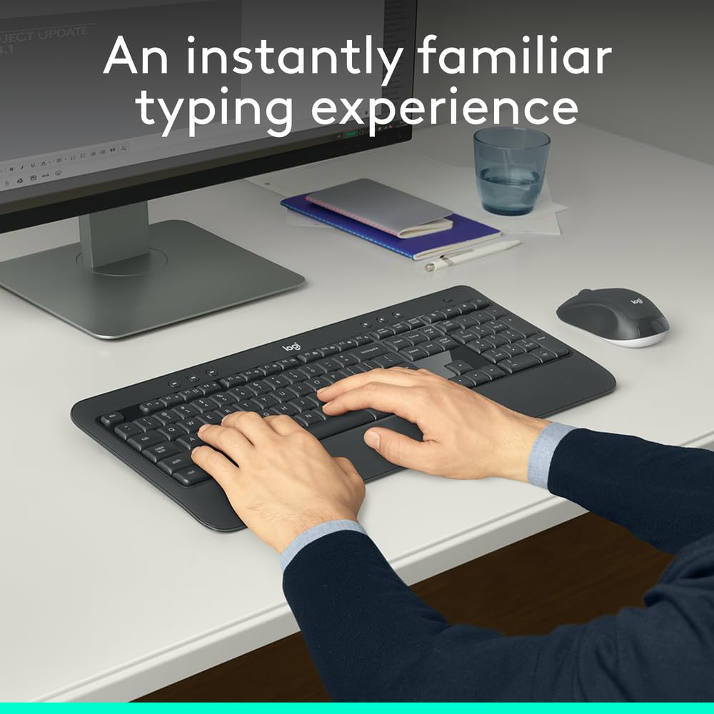 Person typing on a keyboard with a monitor, mouse, and cup in the background.