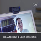 Webcam on a laptop screen with a person's face displayed, set against a blurred bookshelf background.