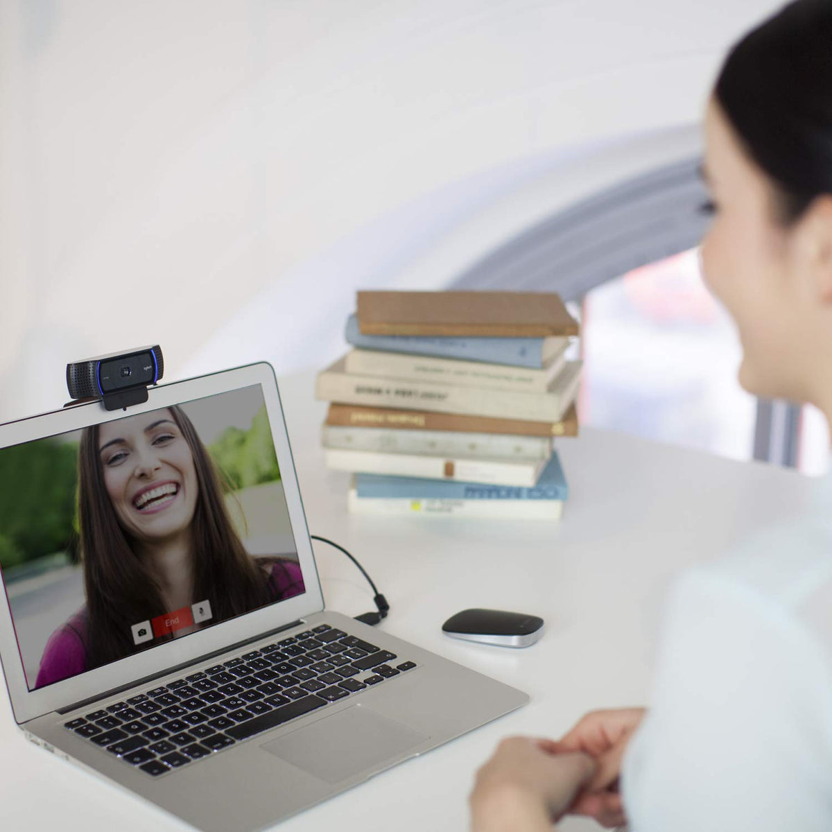 Person using a laptop for a video call with books in the background