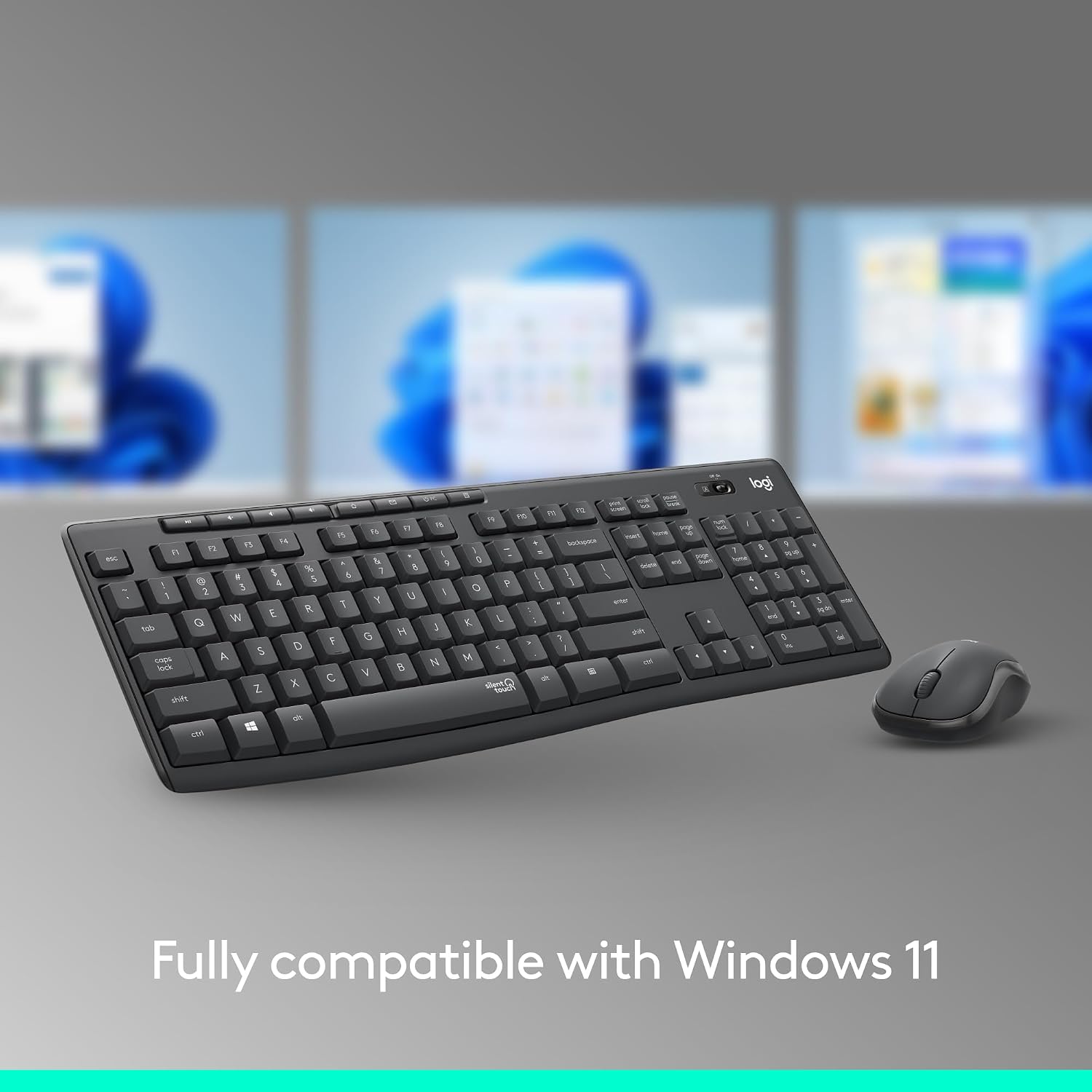 Black keyboard and mouse set on a gray surface with blurred screens in the background, featuring text 'Fully compatible with Windows 11'.