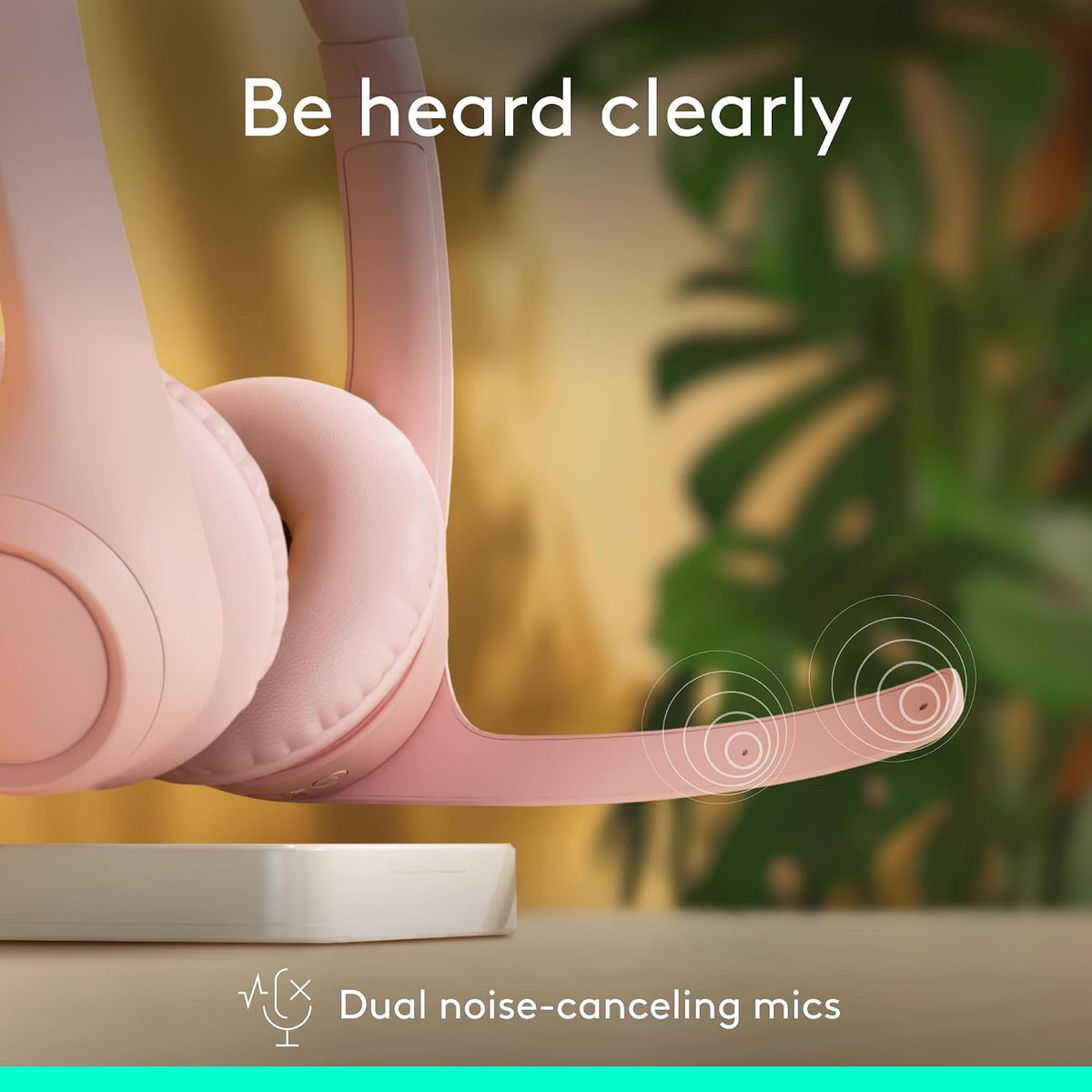 Pink headphones with dual noise-canceling mics feature against a blurred natural background