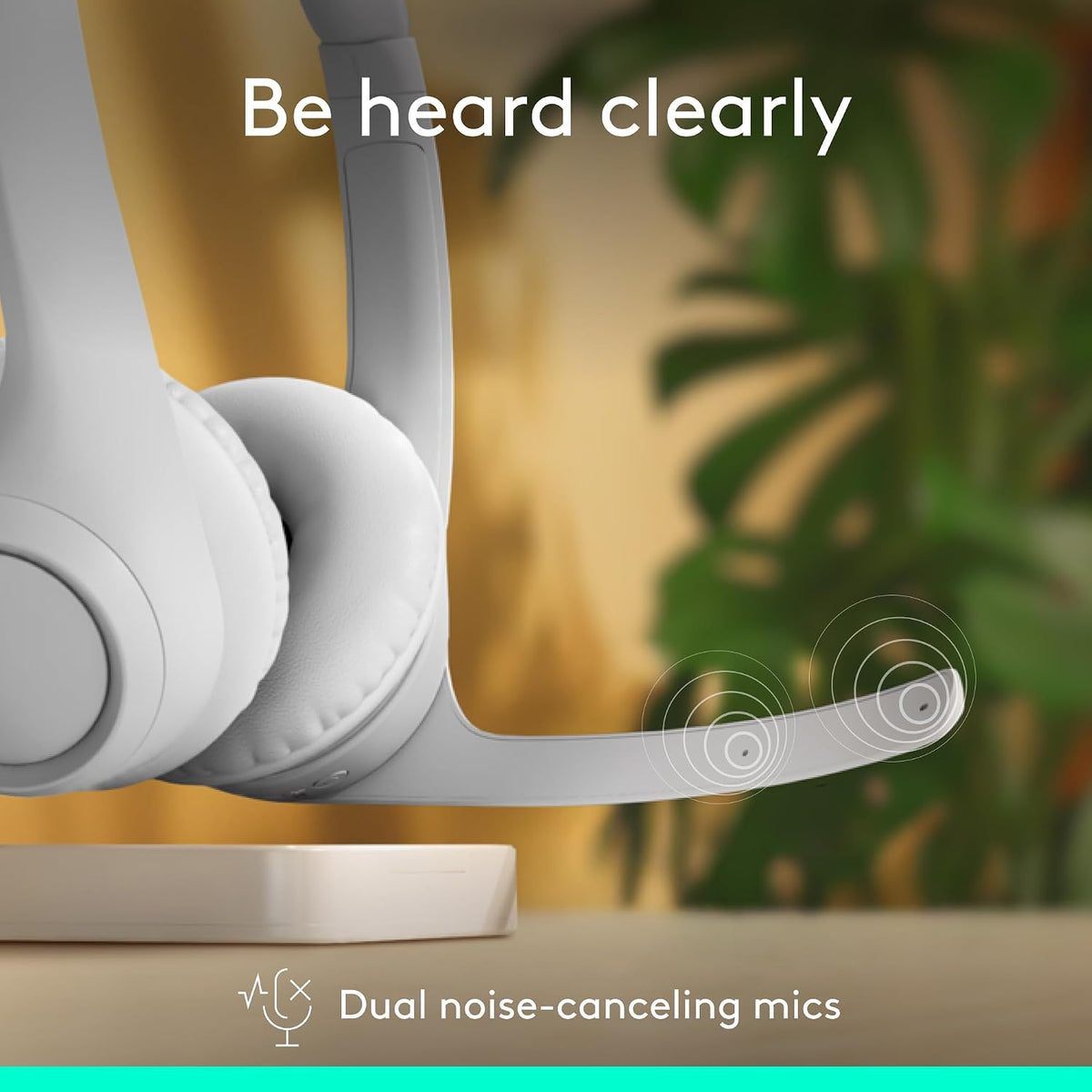 White headphones with dual noise-canceling mics on a blurred indoor background