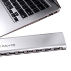 A silver aluminum 7-port USB hub with the brand name CADYCE printed on the side, shown next to a laptop keyboard on a white background.