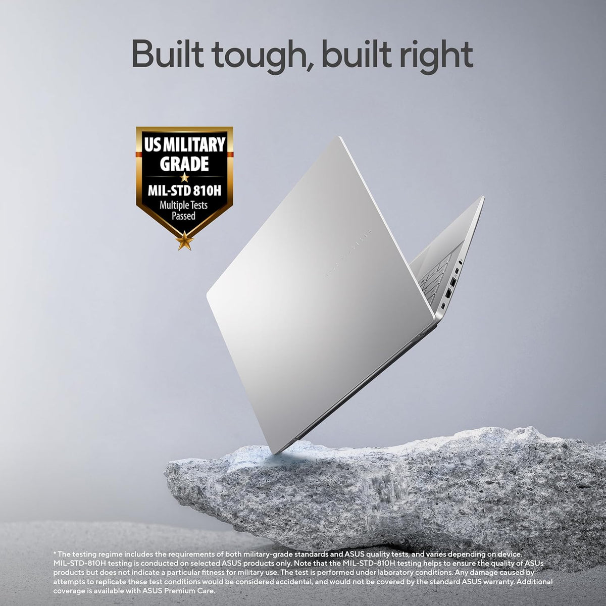 A silver ASUS laptop floating above a gray rock against a light gray background, with the headline 'Built tough, built right' and a 'US Military Grade MIL-STD 810H' badge. Small disclaimer text appears at the bottom.