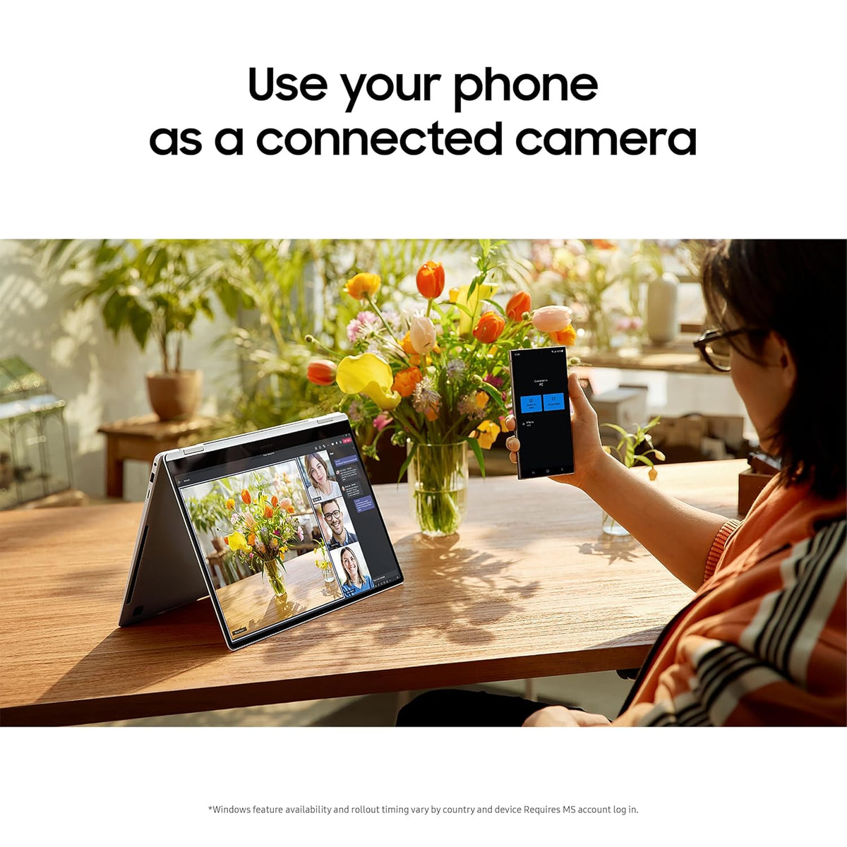 A woman sits at a wooden table in a sunlit indoor setting, holding a smartphone that displays a camera app, while a tablet on a stand shows a video call interface. Large text at the top reads, 'Use your phone as a connected camera.
