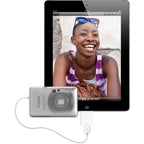 A silver Canon digital camera connected via a white USB cable to the front of a black tablet, with a smiling woman's photo displayed on the tablet screen.