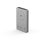 A slim rectangular portable power bank in brushed silver metal, shown at a three-quarter angle on a clean white background. The back features a circular wireless charging symbol and small printed specifications.
