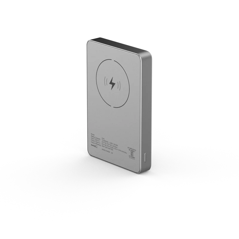 A slim rectangular portable power bank in brushed silver metal, shown at a three-quarter angle on a clean white background. The back features a circular wireless charging symbol and small printed specifications.