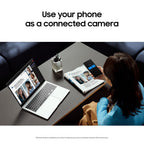 A woman seated at a table uses a smartphone as a camera, with a laptop and magazine nearby. Large text at the top reads, 'Use your phone as a connected camera.