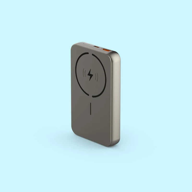 A slim, rectangular portable power bank in a metallic taupe-gray finish, featuring a black wireless charging symbol on its front face, set against a solid light blue background.