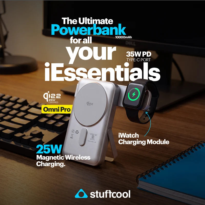 A silver Stuffcool Omni Pro power bank with built-in wireless charging pads, shown charging an Apple Watch on a wooden desk with a keyboard and monitor in the background. Text overlays highlight its 10000mAh capacity, 35W PD type-C port, 25W magnetic wireless charging, and Qi2.