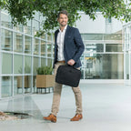 Man holding a black briefcase in an office setting with modern architecture.