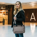 Woman holding a gray briefcase in an indoor setting with a modern design.
