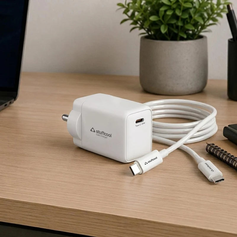 White charging adapter with cable on a wooden desk with a plant in the background