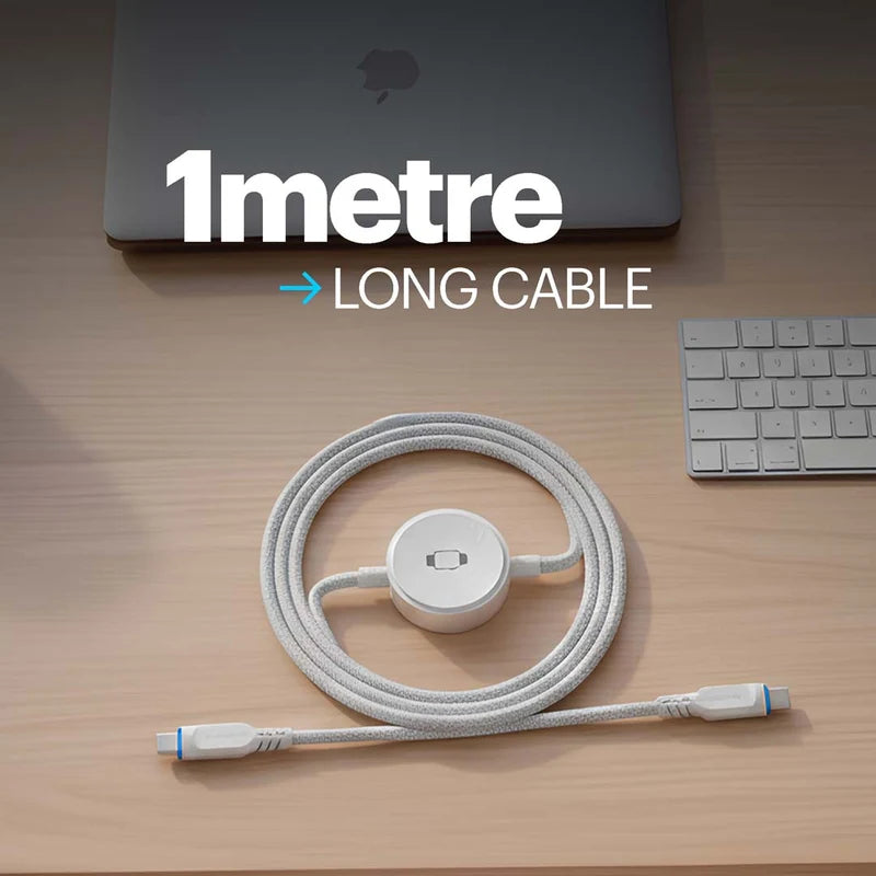 A white braided USB-C cable with a central hub connector, coiled on a light wood desk next to a laptop and keyboard. Large text overlay reads '1metre LONG CABLE'.