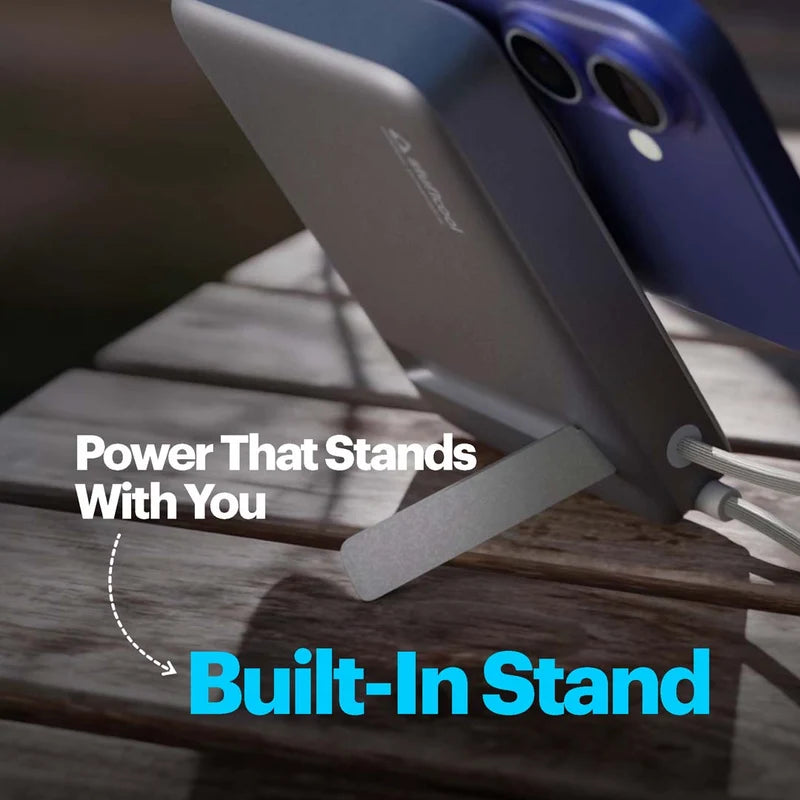 A close-up of a gray built-in phone stand holding a smartphone, with overlaid text reading 'Power That Stands With You' and 'Built-In Stand' on a wooden surface.