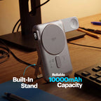 A silver portable power bank with a built-in stand, shown on a wooden desk next to a keyboard and monitor stand. Text overlays highlight its 'Built-In Stand' and 'Reliable 10000mAh Capacity'.