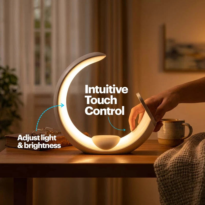 A crescent-shaped LED night light with a built-in charging port, shown on a wooden table in a cozy room. A hand is touching the side of the light to demonstrate touch control.
