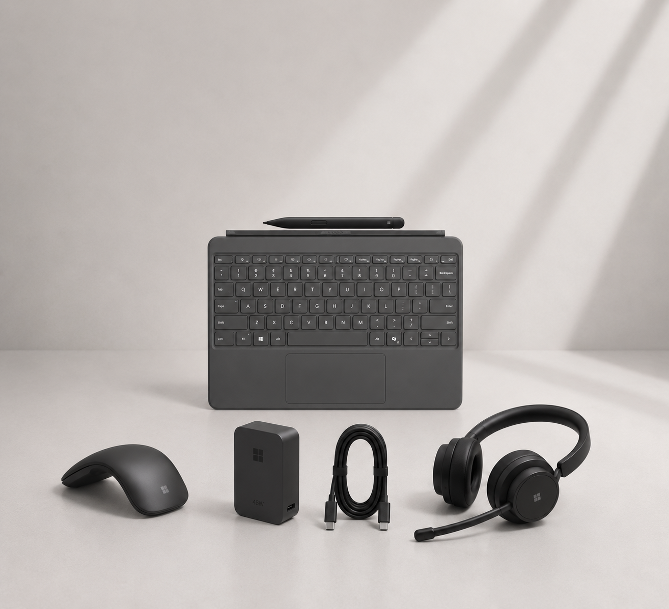 Microsoft keyboard, mouse, earbuds, and other accessories on a white surface with a gray background