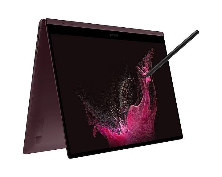 A Samsung convertible laptop shown open at an angle with the screen on, displaying a pink abstract wallpaper, and a stylus resting on the top right edge, against a plain white background.