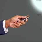 Hand holding a silver lighter against a gray background