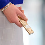 Hand holding a gold flashlight with a blurred background