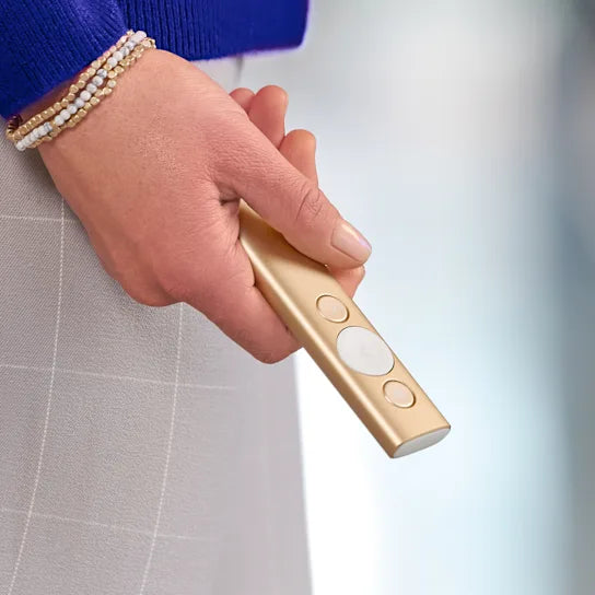 Hand holding a gold flashlight with a blurred background