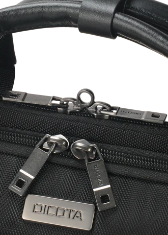 Close-up of a black woven bag with a black leather handle and silver-tone hardware, including two zipper pulls and a metal brand plate reading DICOTA.