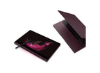 A dark plum-colored tablet shown closed with a stylus resting on its screen, alongside an open view of the same device showing its keyboard and screen bezel, on a clean white background.