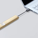 Gold USB-C adapter connected to a laptop on a light gray background