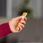 Hand holding a gold electronic device with a blurred background