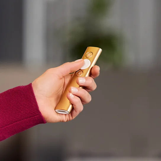 Hand holding a gold electronic device with a blurred background