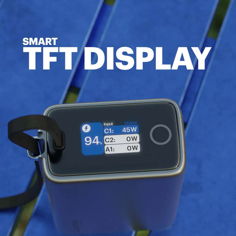 A portable electronic device with a black TFT display screen showing battery status and power metrics, placed on a blue slatted surface. Large white text at the top reads 'SMART TFT DISPLAY'.